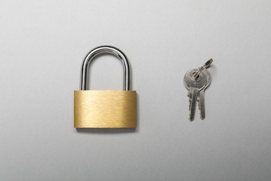 Steel padlock with keys on grey background, top view