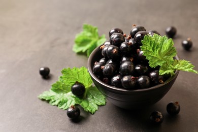 Ripe blackcurrants and leaves on grey background, closeup. Space for text