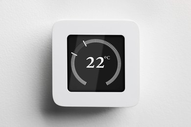 Image of Thermostat displaying temperature in Celsius scale. Smart home device on white wall