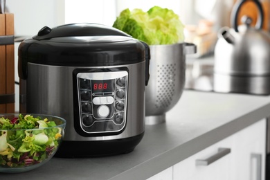 Photo of Modern electric multi cooker and food on kitchen countertop. Space for text