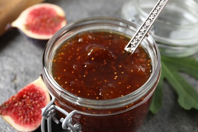 Jar of tasty sweet jam and fresh figs on table, closeup