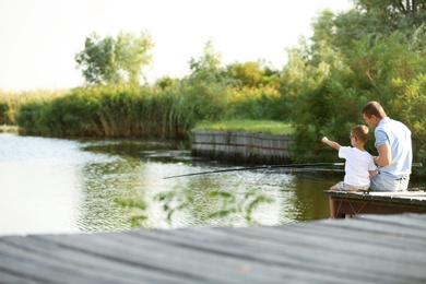 Dad and son fishing together on sunny day. Space for text