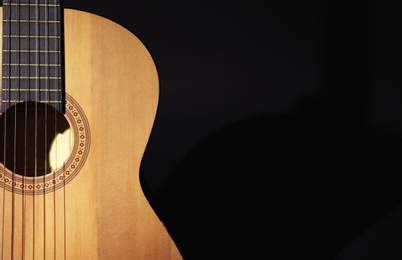 Photo of Acoustic guitar on black background, closeup. Space for text
