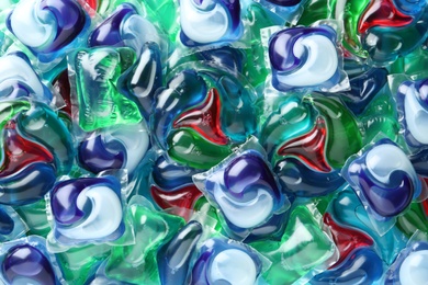 Many different laundry capsules as background, top view