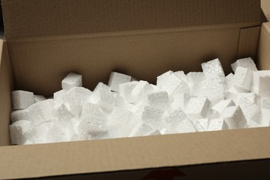 Photo of Open cardboard box with pieces of polystyrene foam, closeup. Packaging goods