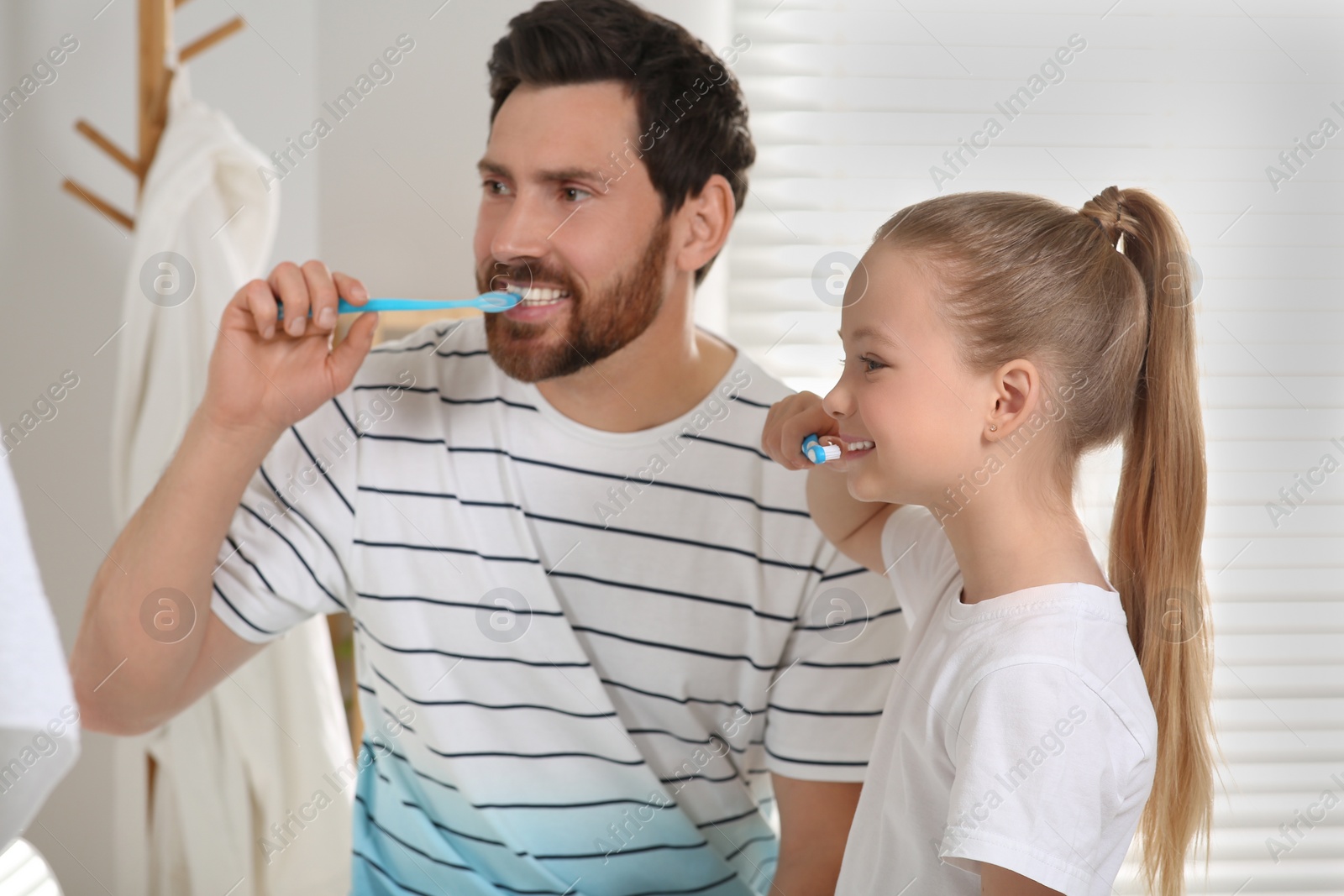 Photo of Father and his daughter brushing teeth together in bathroom