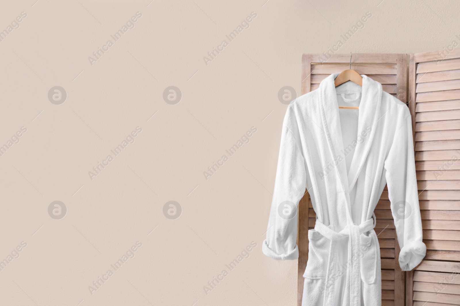 Photo of Soft comfortable bathrobe hanging on folding screen in stylish room interior