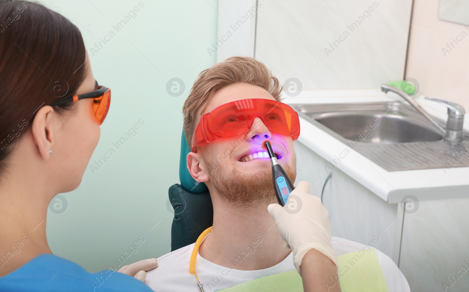 Photo of Professional dentist working with patient in modern clinic. Teeth whitening