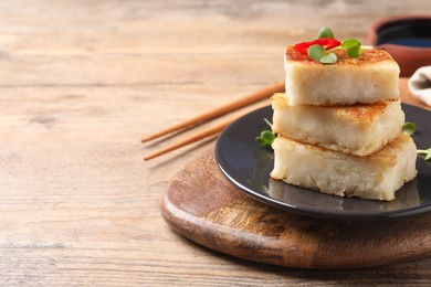 Photo of Delicious turnip cake with microgreens served on wooden table, closeup. Space for text