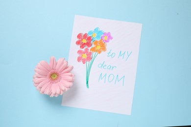Photo of Handmade greeting card for Mother's day and flower on light blue background, flat lay