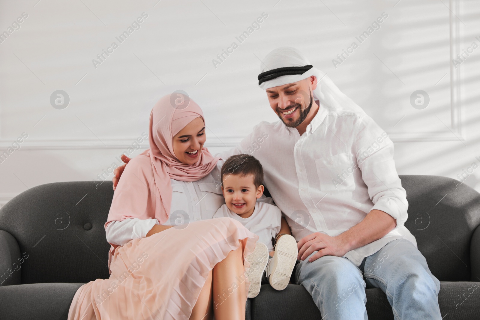 Photo of Happy Muslim family spending time together on sofa at home