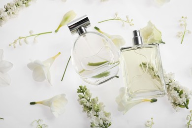 Photo of Luxury perfumes on spring floral decor, top view