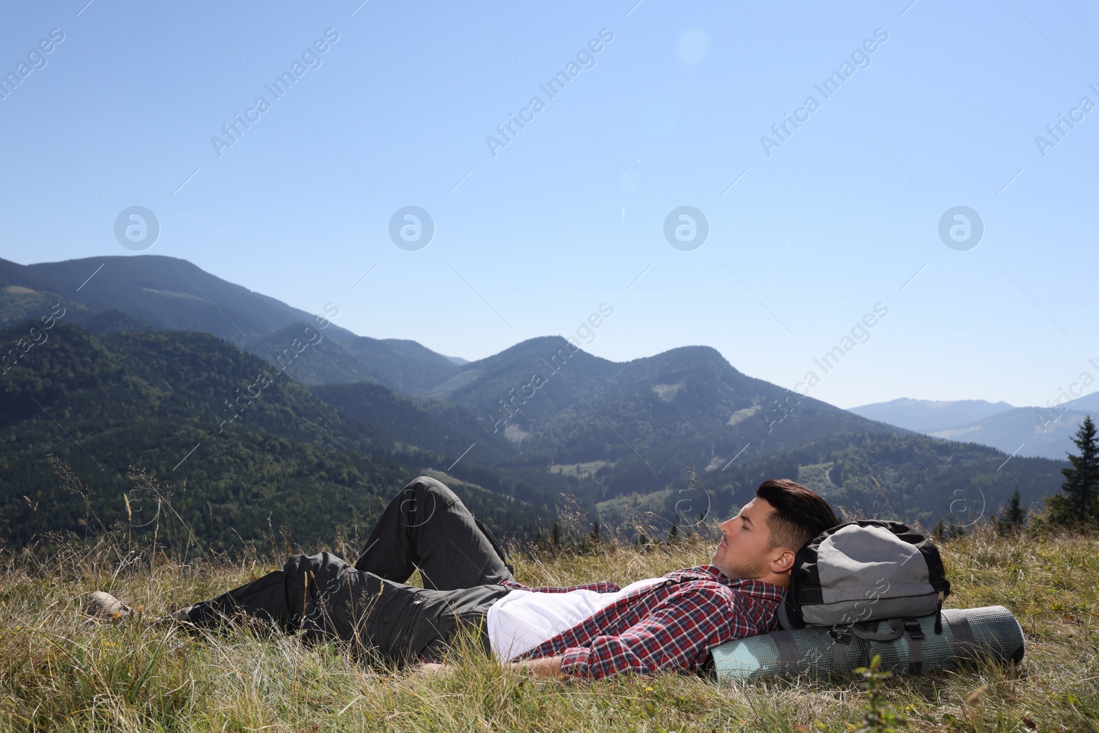 Photo of Tourist with backpack resting on ground in mountains