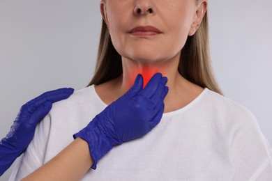 Image of Endocrinologist examining thyroid gland of patient on light grey background, closeup