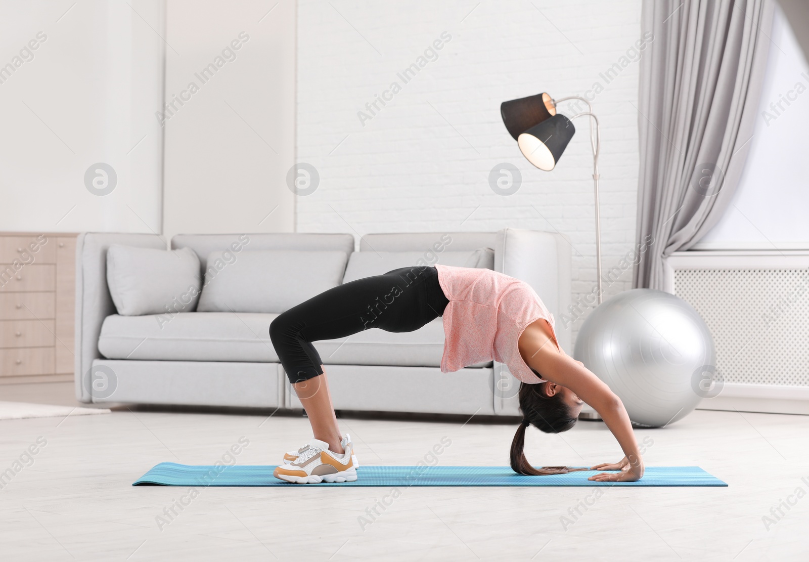 Photo of Young woman in fitness clothes doing exercise at home