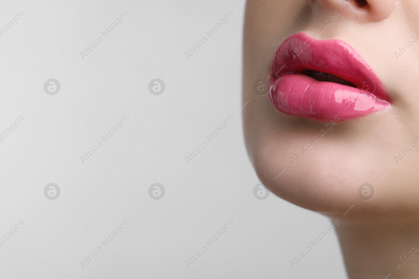 Photo of Closeup view of beautiful young woman with perfect lips makeup on light grey background. Space for text