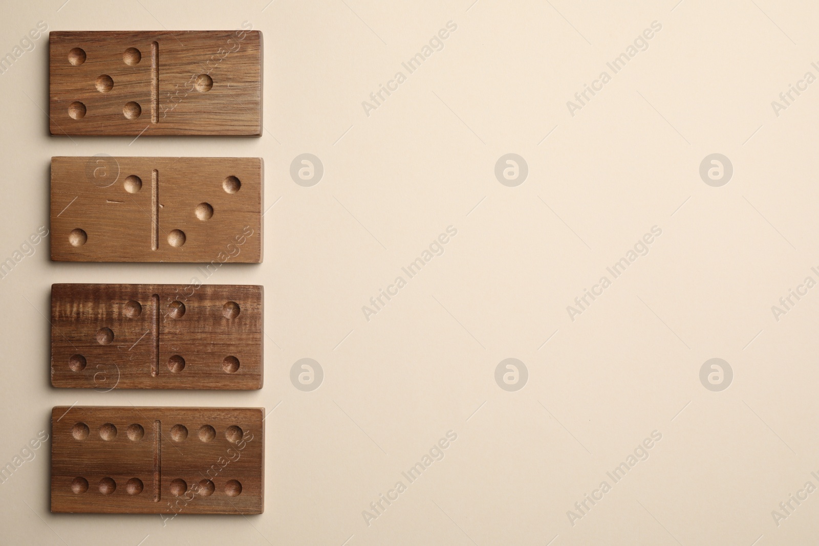 Photo of Wooden domino tiles on beige background, flat lay. Space for text