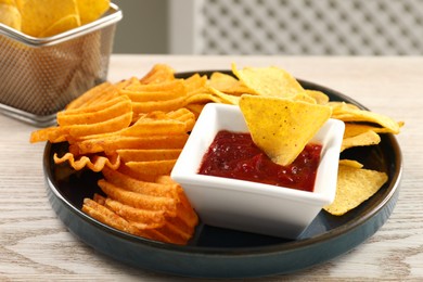 Photo of Tasty tortilla and ridged chips with ketchup on white wooden table, closeup