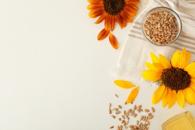 Photo of Sunflowers, oil and seeds on white table, flat lay. Space for text