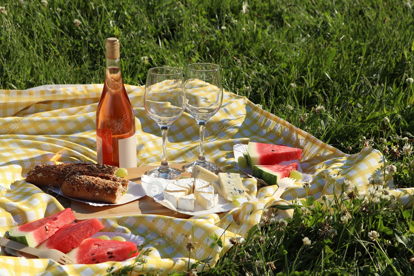 Photo of Picnic blanket with delicious food and wine on green grass outdoors