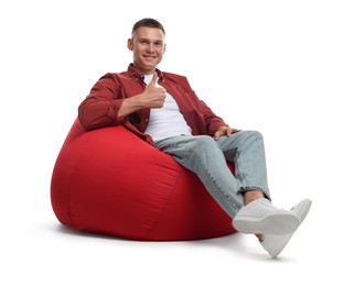 Photo of Smiling man showing thumb up on red bean bag chair against white background