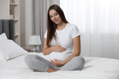 Beautiful pregnant woman with long hair in bedroom