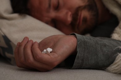 Photo of Depressed man with antidepressants sleeping on bed, selective focus