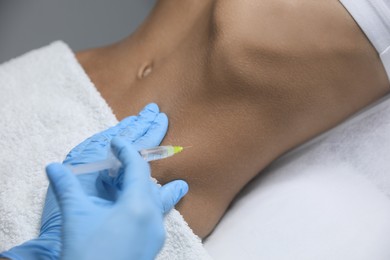 Photo of Young woman getting belly injection in salon, closeup