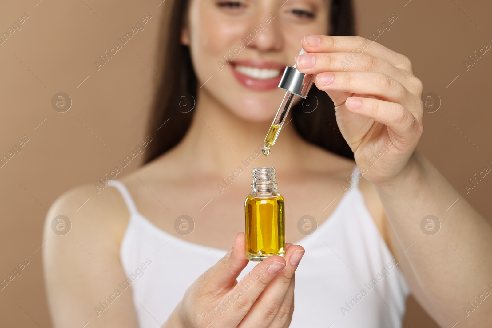 Photo of Woman with essential oil on brown background, selective focus