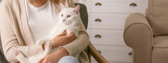 Young woman with her beautiful white cat at home, space for text. Banner design