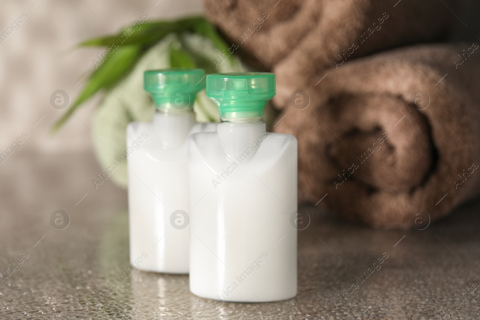 Photo of Mini bottles of cosmetic products on grey textured table