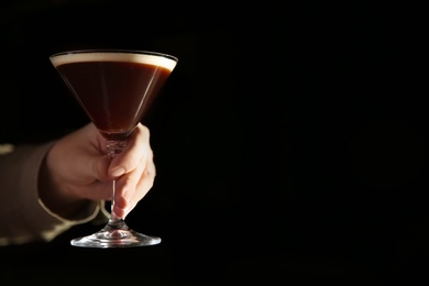 Photo of Barman holding espresso martini cocktail in darkness, closeup. Space for text