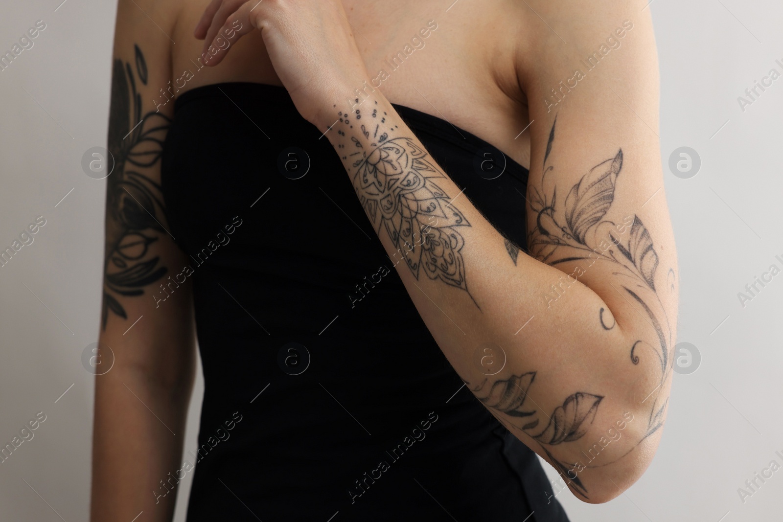 Photo of Woman with cool tattoos on light background, closeup