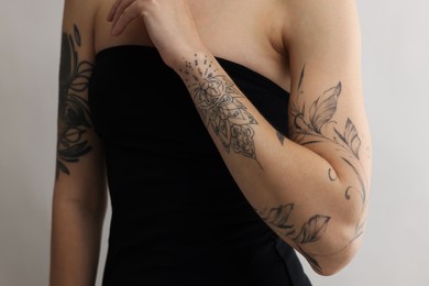 Woman with cool tattoos on light background, closeup