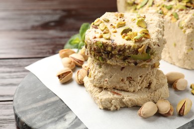 Photo of Pieces of tasty halva with pistachios on table, closeup. Space for text