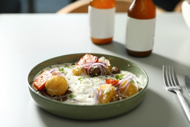 Photo of Beer and tasty dish served on light table, closeup