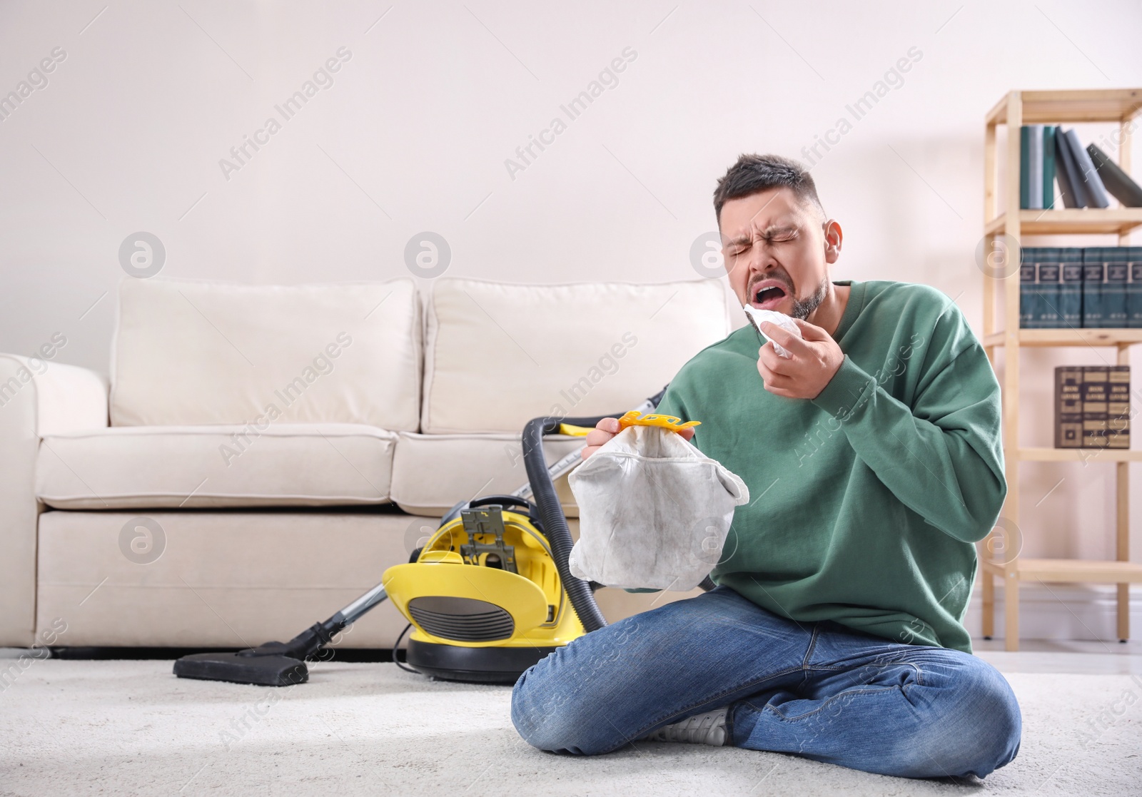 Photo of Man with vacuum cleaner bag suffering from dust allergy at home