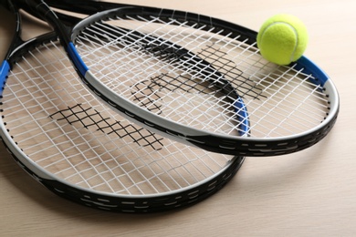 Tennis rackets and ball on wooden table, closeup. Sports equipment