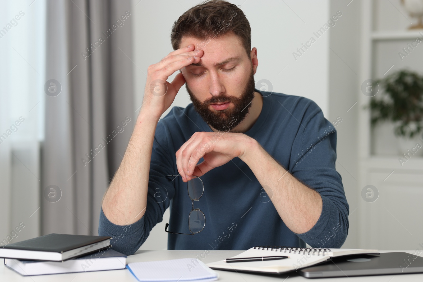 Photo of Overwhelmed man with glasses at table indoors