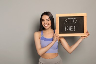 Photo of Happy woman holding chalkboard with words Keto Diet on light grey background