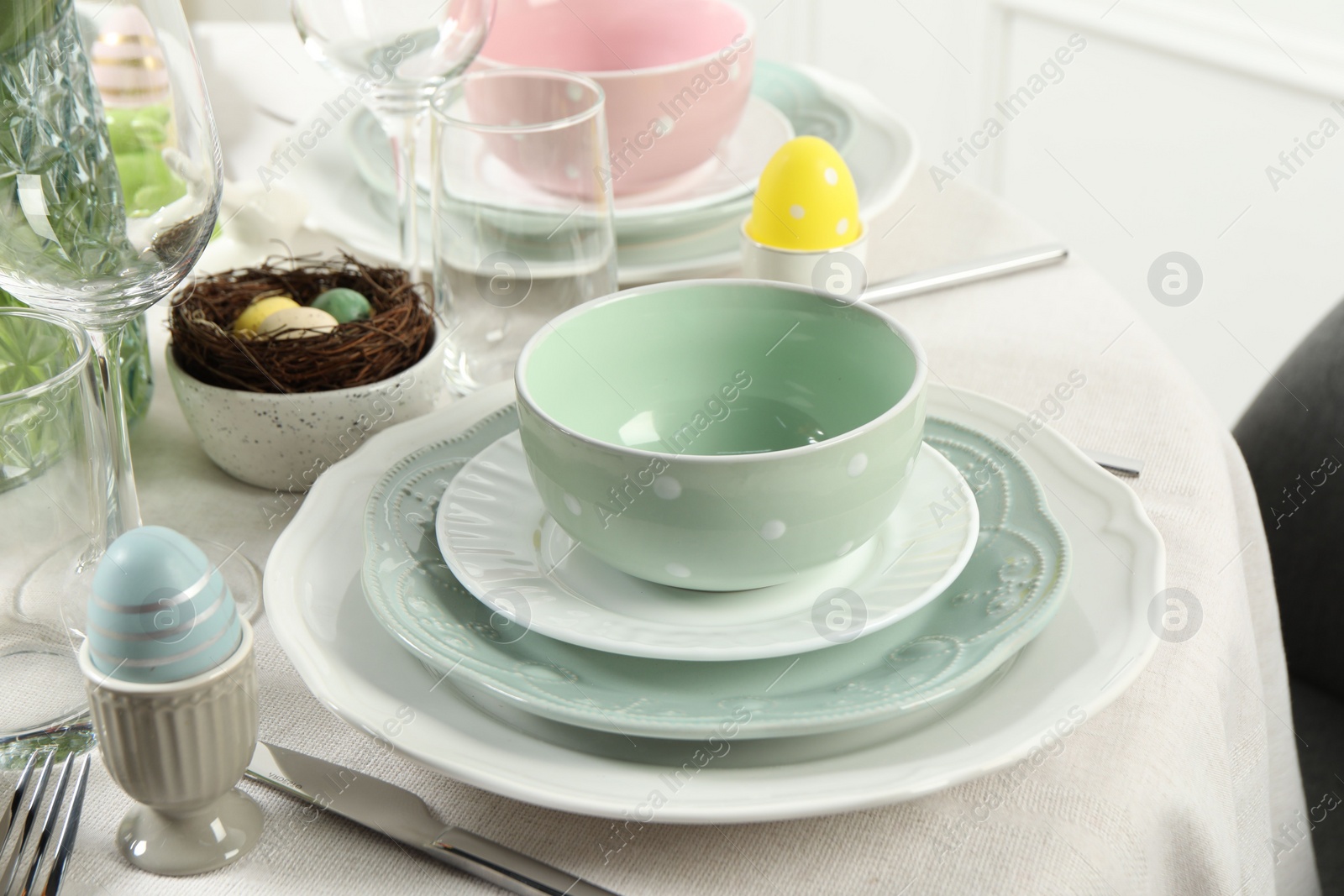 Photo of Easter celebration. Festive table setting with elegant dishware and painted eggs