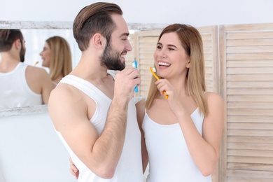 Photo of Young couple brushing teeth together in bathroom