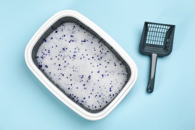Photo of Cat litter tray with filler and scoop on light blue background, flat lay