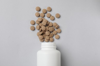 Photo of Vitamin pills and bottle on light grey background, top view