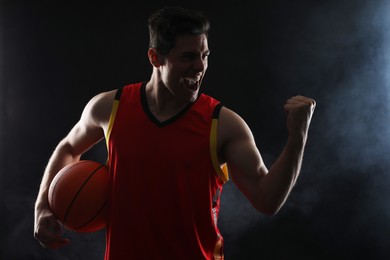 Photo of Basketball player with ball on black background