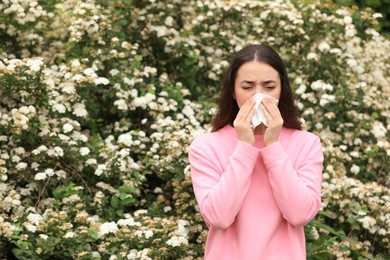 Photo of Woman suffering from seasonal pollen allergy near blossoming tree on spring day