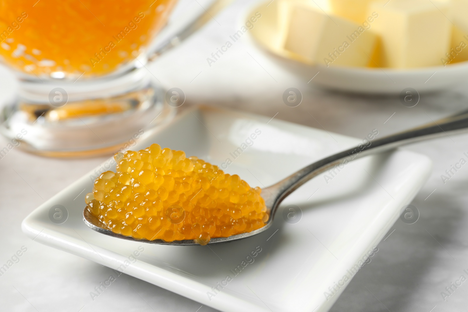 Photo of Fresh pike caviar in spoon on white marble table, closeup