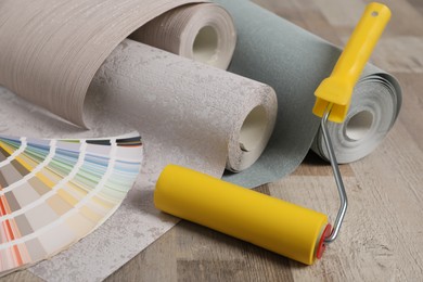 Photo of Wall paper rolls, color palette and tool on wooden floor