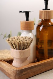 Cleaning brush, bottles and sponge on table