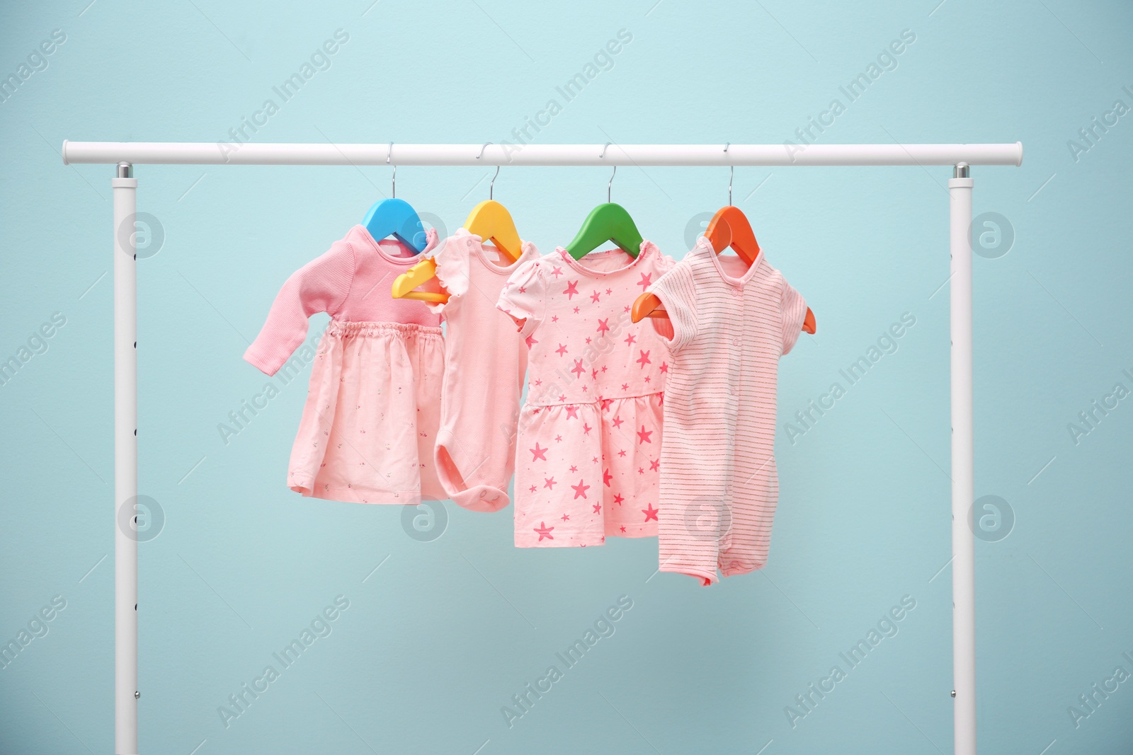 Photo of Baby clothes hanging on rack against color background